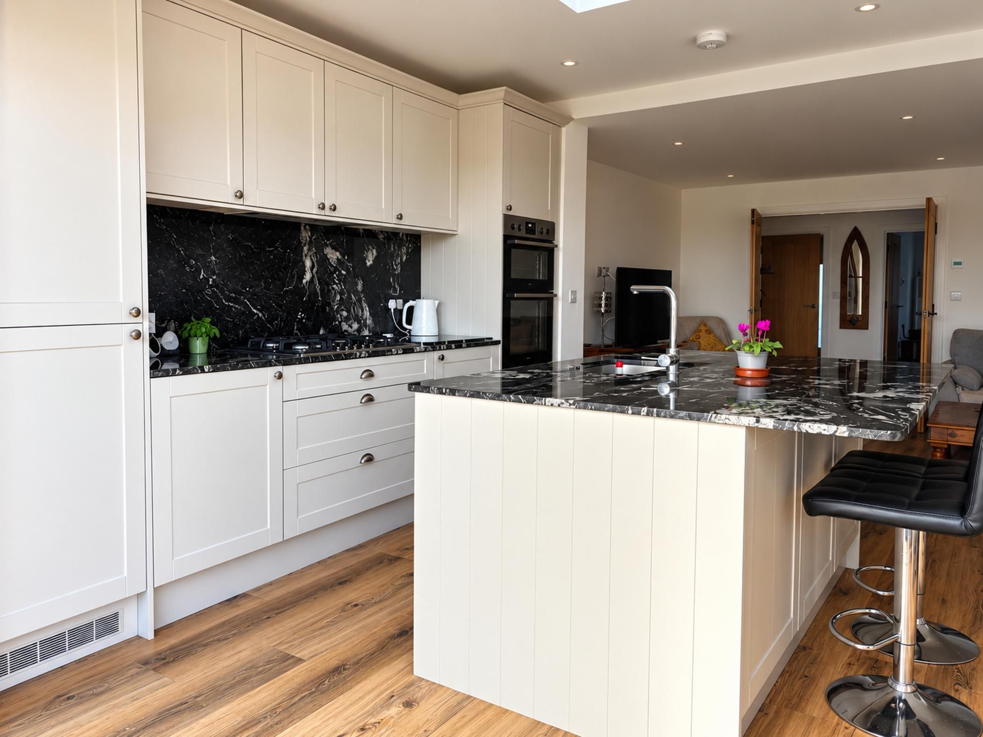 A modern kitchen with white cabinetry, a black marble countertop, and a central island with bar stools.