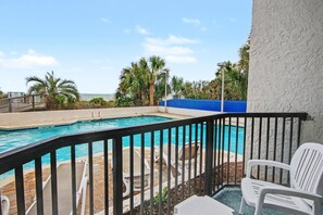 A pool with a view of the ocean, surrounded by palm trees and a blue fence. - Pool View 1BR + Beach Access + Dog Friendly (Myrtle Beach)