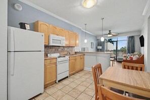 A kitchen with wooden cabinets, a white refrigerator, a microwave, and a stove.