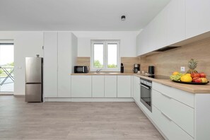 Eine moderne Küche mit weißen Schränken, einem Edelstahlkühlschrank, einer Mikrowelle und einer Kaffeemaschine.