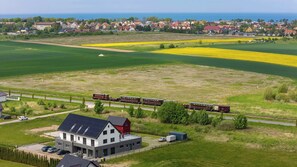 Ländliche Landschaft mit einem Zug, Feldern und einem Haus mit Solaranlage.