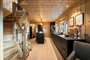 Un interno in legno con una scala, un'isola centrale e un angolo cucina.