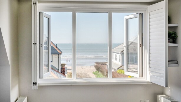 Ein Zimmer mit großem Fenster und Blick auf Strand und Häuser.