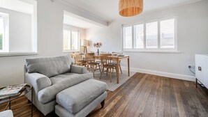 Ein Wohnzimmer mit grauem Sofa, einem Holzesstisch und einer Pendelleuchte.