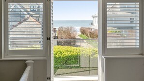 Blick von einem Balkon auf ein klares Meer und Wohnhäuser im Hintergrund.
