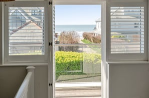 Blick von einem Balkon auf ein klares Meer und Wohnhäuser im Hintergrund.