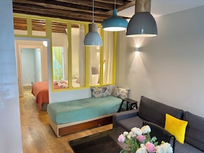 Ein modernes Zimmer mit Bett, Sofa, Couchtisch mit Blumen und Spiegel.