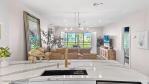 A modern kitchen with a marble countertop, a gold faucet, and a built-in sink.