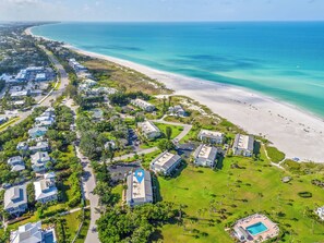 Luftaufnahme eines Küstenresorts mit mehreren Gebäuden, einem Strand und einem Schwimmbecken.