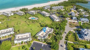 An aerial view of a coastal resort with multiple buildings, a beach, and a swimming pool.