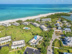 Luftaufnahme eines Küstenresorts mit mehreren Gebäuden, einem Strand und einem Swimmingpool.