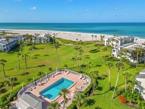 Ein Resort mit Swimmingpool, Blick auf den Strand und Palmen.
