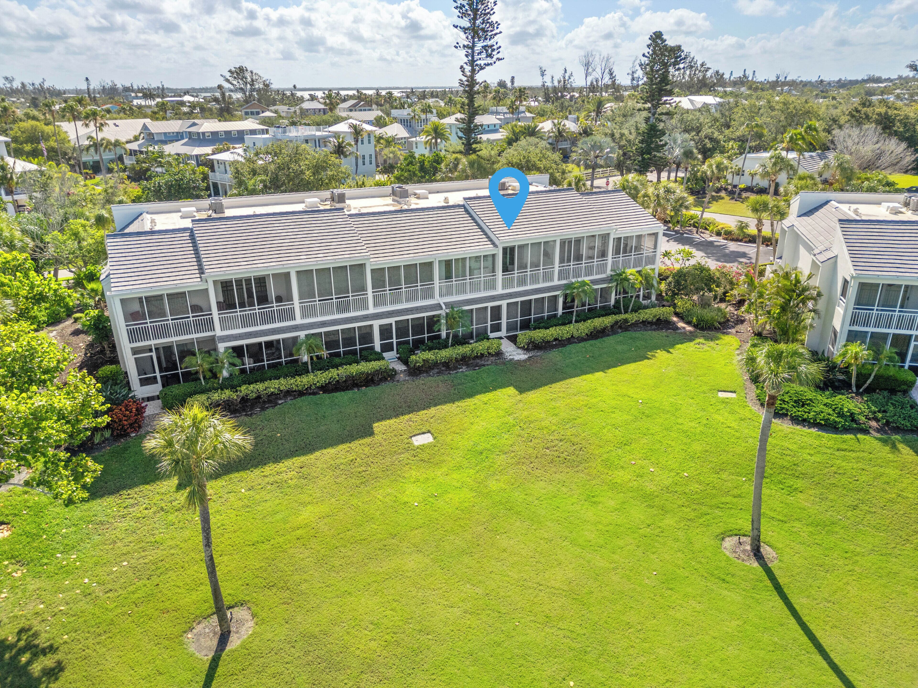 A multi-story building with a flat roof, surrounded by well-maintained lawns and palm trees.