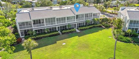 A multi-story building with a flat roof, surrounded by well-maintained lawns and palm trees.