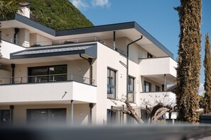 Een modern gebouw met twee verdiepingen, balkons, grote ramen en een plat dak.