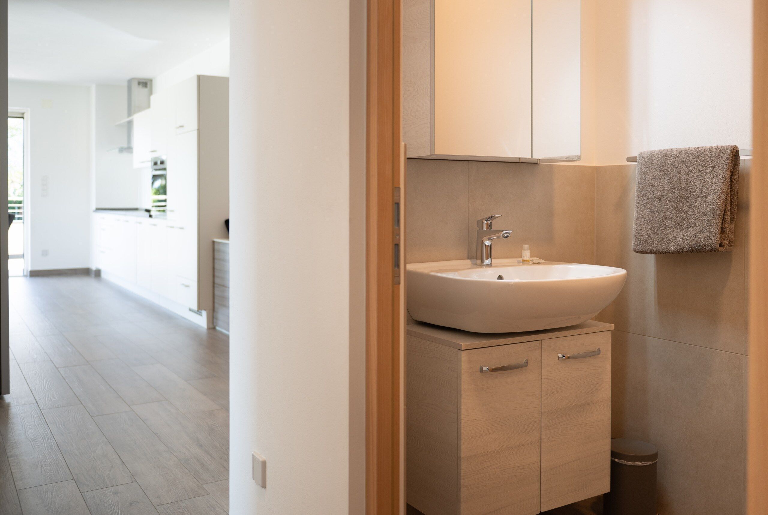 A modern bathroom with a freestanding sink, wooden cabinetry, and a towel hanging on the wall.
