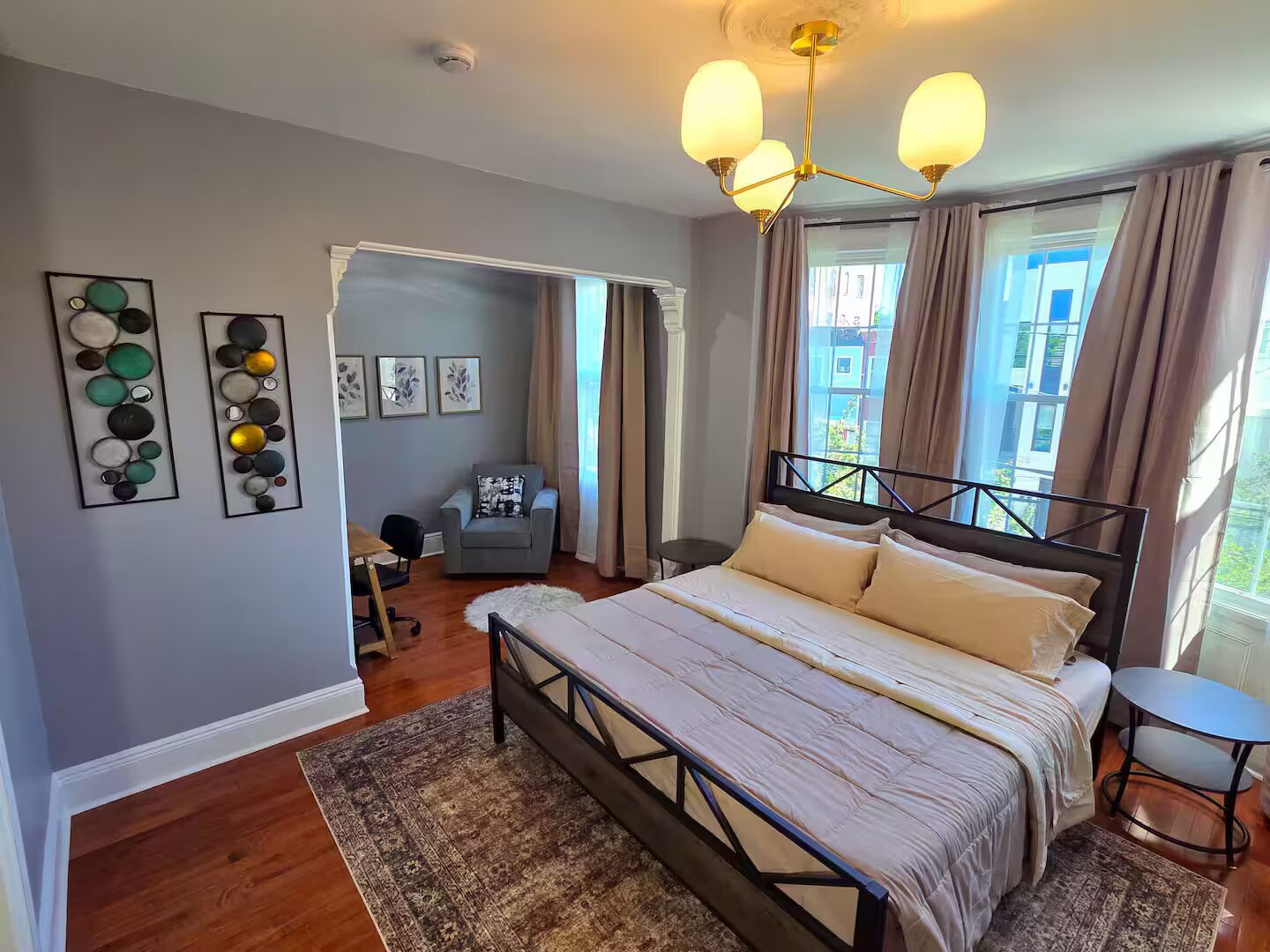 A bedroom with a bed, a chair, a desk, and a view of the outside.
