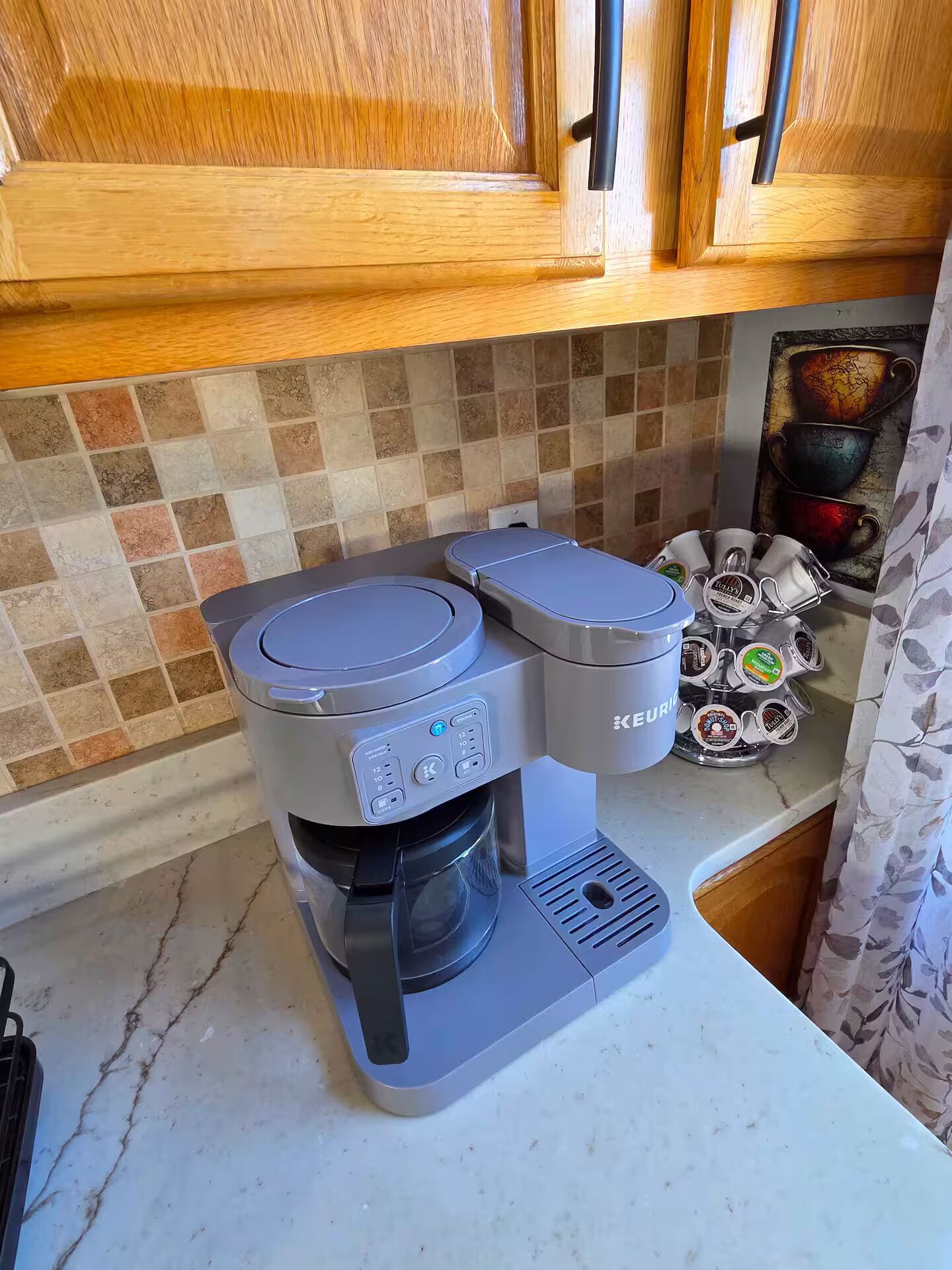Una cocina con cafetera, un soporte para tazas y salpicadero de azulejos.