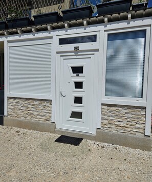 A building with a white door, stone wall, and two garage doors. - Apartment "North Star" (Dürrwangen)
