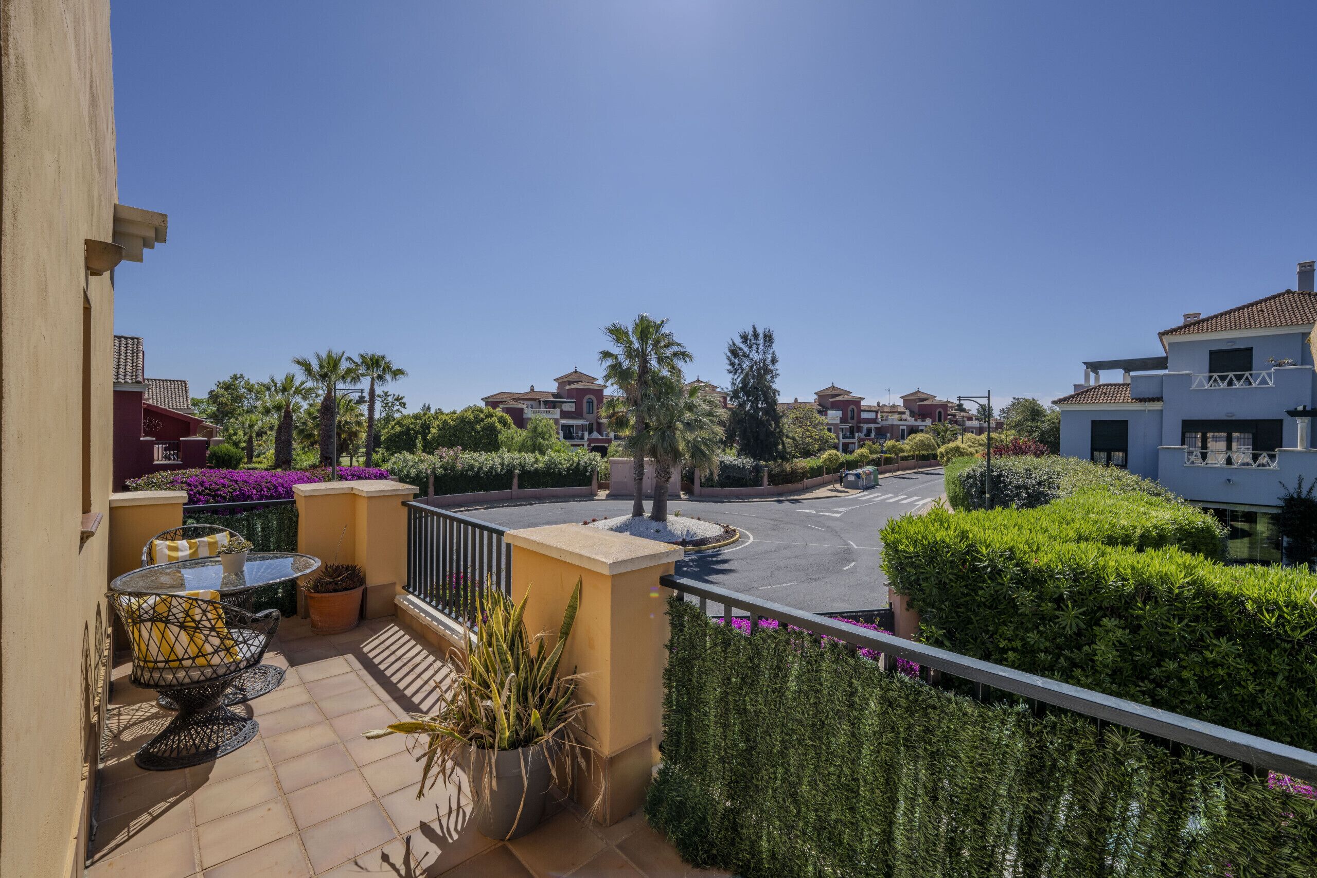 Un quartier résidentiel avec des balcons, des plantes en pot et un ciel dégagé.