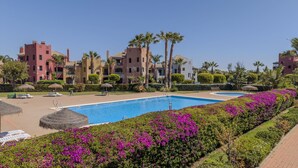 Un resort con piscina, palmeras y un cielo azul cristalino.