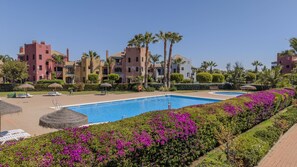 Ein Resort mit Swimmingpool, Palmen und wolkenlosem, blauem Himmel.
