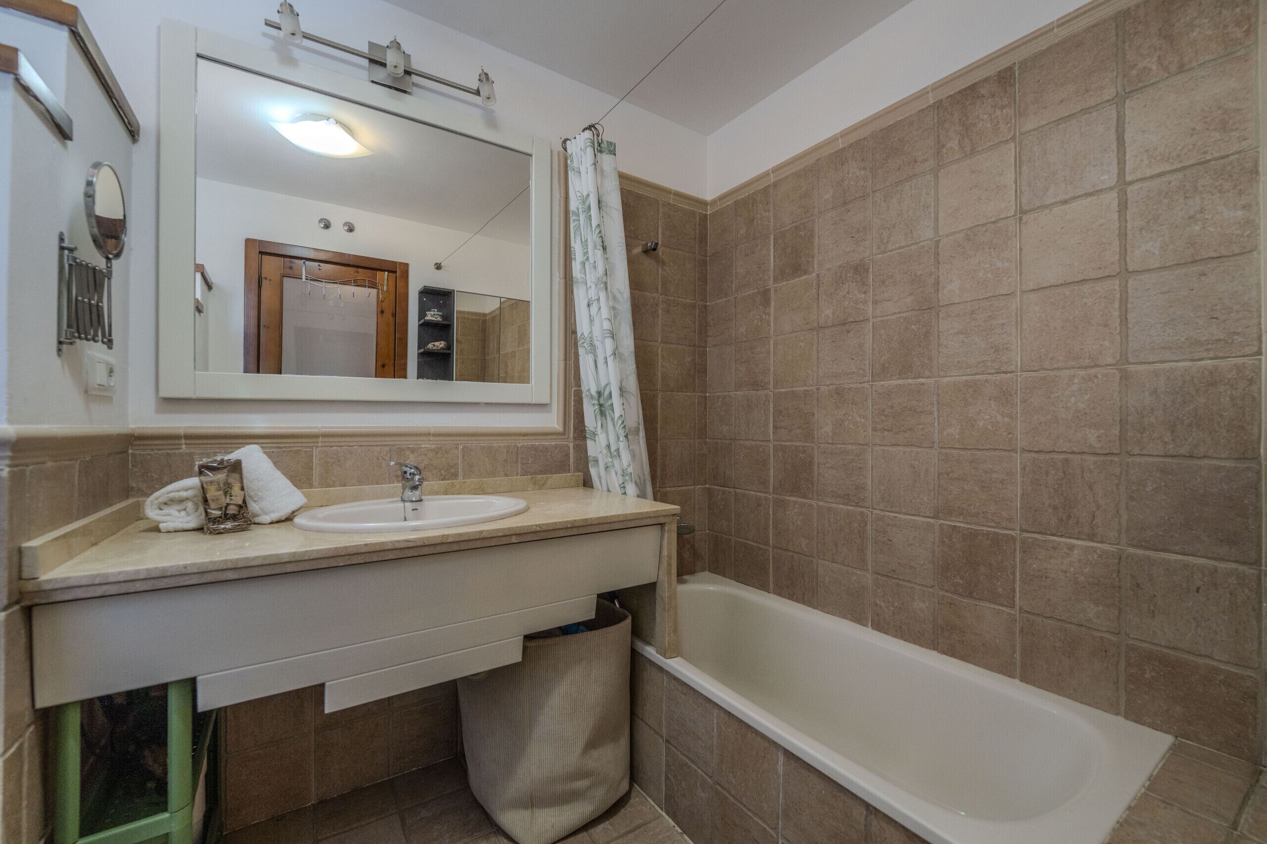 A bathroom with a sink, mirror, and bathtub.