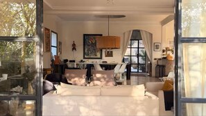 A spacious living room with a large sofa, a dining area with a table and chairs, and a kitchen in the background.