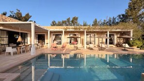 A poolside area with lounge chairs and umbrellas, a covered seating area, and a clear view of the pool.