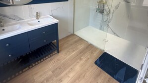 A modern bathroom with a double sink vanity, a glass-enclosed shower, and wooden flooring. - Spacious, newly renovated townhouse (Toul)