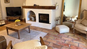 Una sala de estar con chimenea, televisor y un espejo grande.