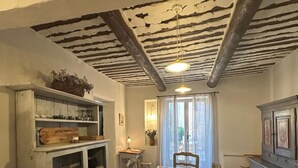 Un comedor con una mesa de madera, sillas, una araña y un techo rústico.