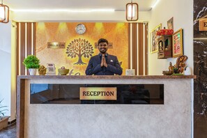 Mostrador de recepción con un reloj, un cartel que dice 'Check In' y un cartel que dice 'Recepción'.