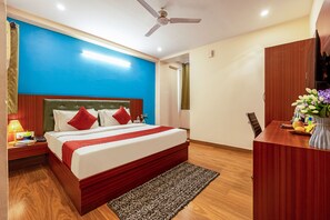 Une chambre d’hôtel comprenant un lit, une table de chevet, une lampe et un bureau avec une chaise.