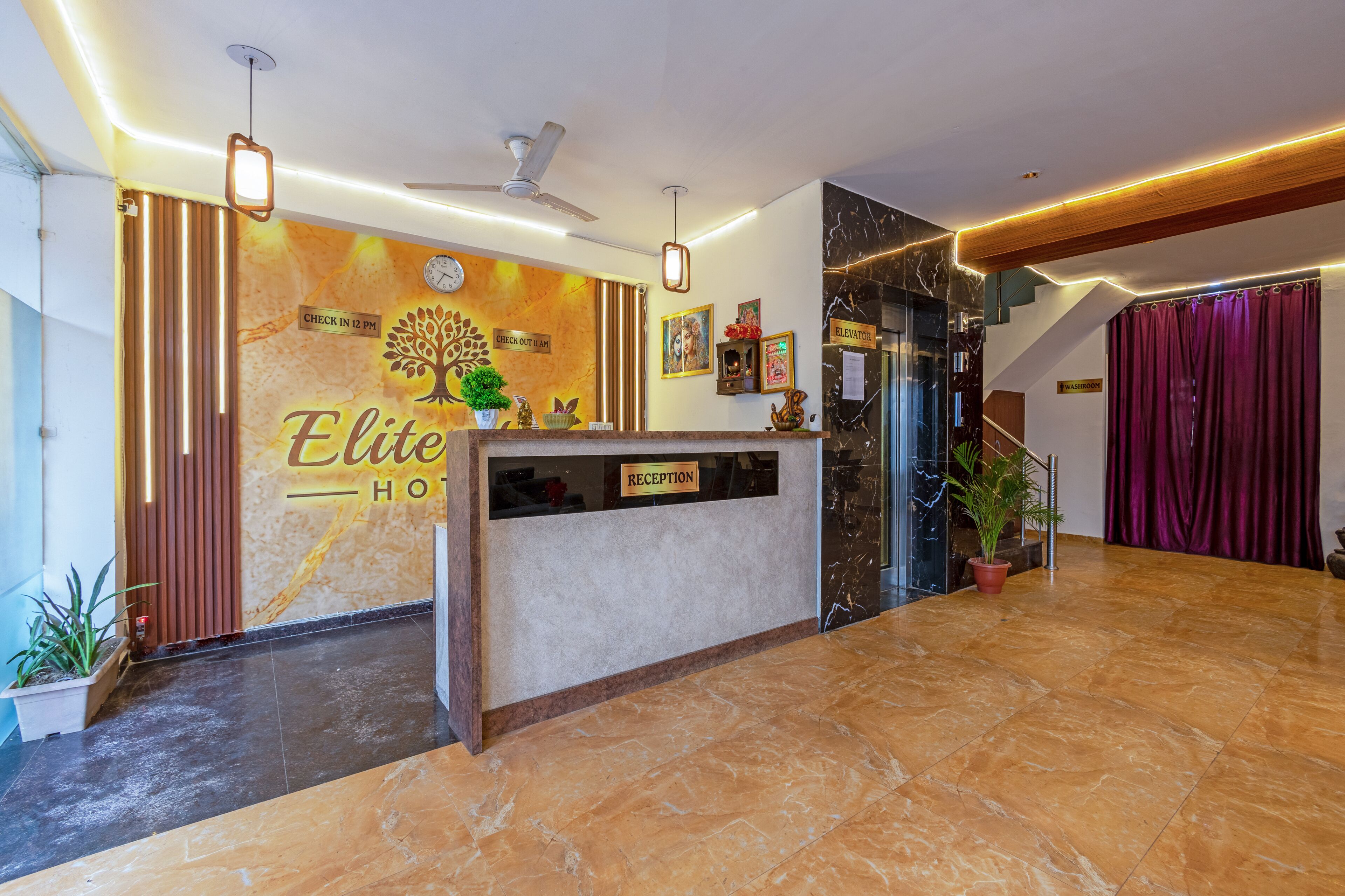 A hotel reception area with a marble floor, a reception desk, a clock, and a ceiling fan.