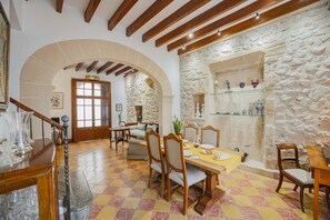 A dining area with a checkered floor, wooden furniture, and a stone wall. - Casa Angels with private pool in the historic center of Pollença (Pollensa)