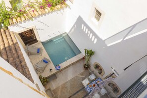 A rooftop pool with a view of the city, surrounded by potted plants and outdoor furniture. - Casa Angels with private pool in the historic center of Pollença (Pollensa)