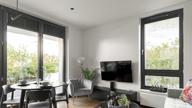 Un soggiorno moderno con zona pranzo, ampie finestre, TV a schermo piatto e divano.