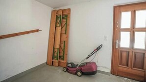 A room with a wooden door, a wooden bench, and a lawnmower. - 4* renovated apartment at the top of the mountain at 1500 m (Goms)