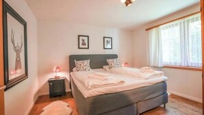 A bedroom with a bed, a nightstand, a lamp, and a framed picture on the wall. - 4* renovated apartment at the top of the mountain at 1500 m (Goms)