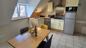 A compact kitchen with a dining area, a microwave, a refrigerator, and a window providing natural light. - L'orée du vignoble - Le Nid, Alsace, self catering Alsace, wine route (Blienschwiller)