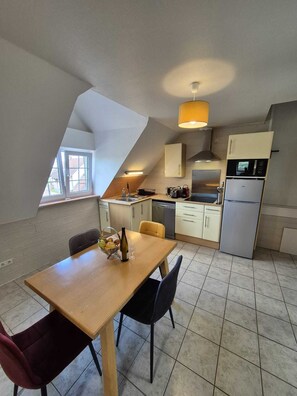 A compact kitchen with a dining area, a microwave, a refrigerator, and a window providing natural light.
