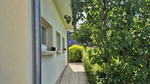 A narrow pathway leading to a building with a yellow facade, a window, and a metal pipe running along the wall. - L'orée du vignoble - Le Nid, Alsace, self catering Alsace, wine route (Blienschwiller)