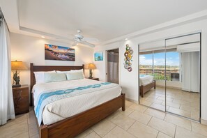 A bedroom with a large bed, a ceiling fan, a balcony with a view, and a sliding glass door. - Spectacular Ocean Views & Updated Interior at Mana Kai Maui Resort #706C (Kihei, Maui)