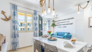 A dining area with a table set for two, a blue sofa, and a wall with a motivational quote. - Apartment 'La Casa Di Chloe' with Wi-Fi and Air Conditioning (Pachino)
