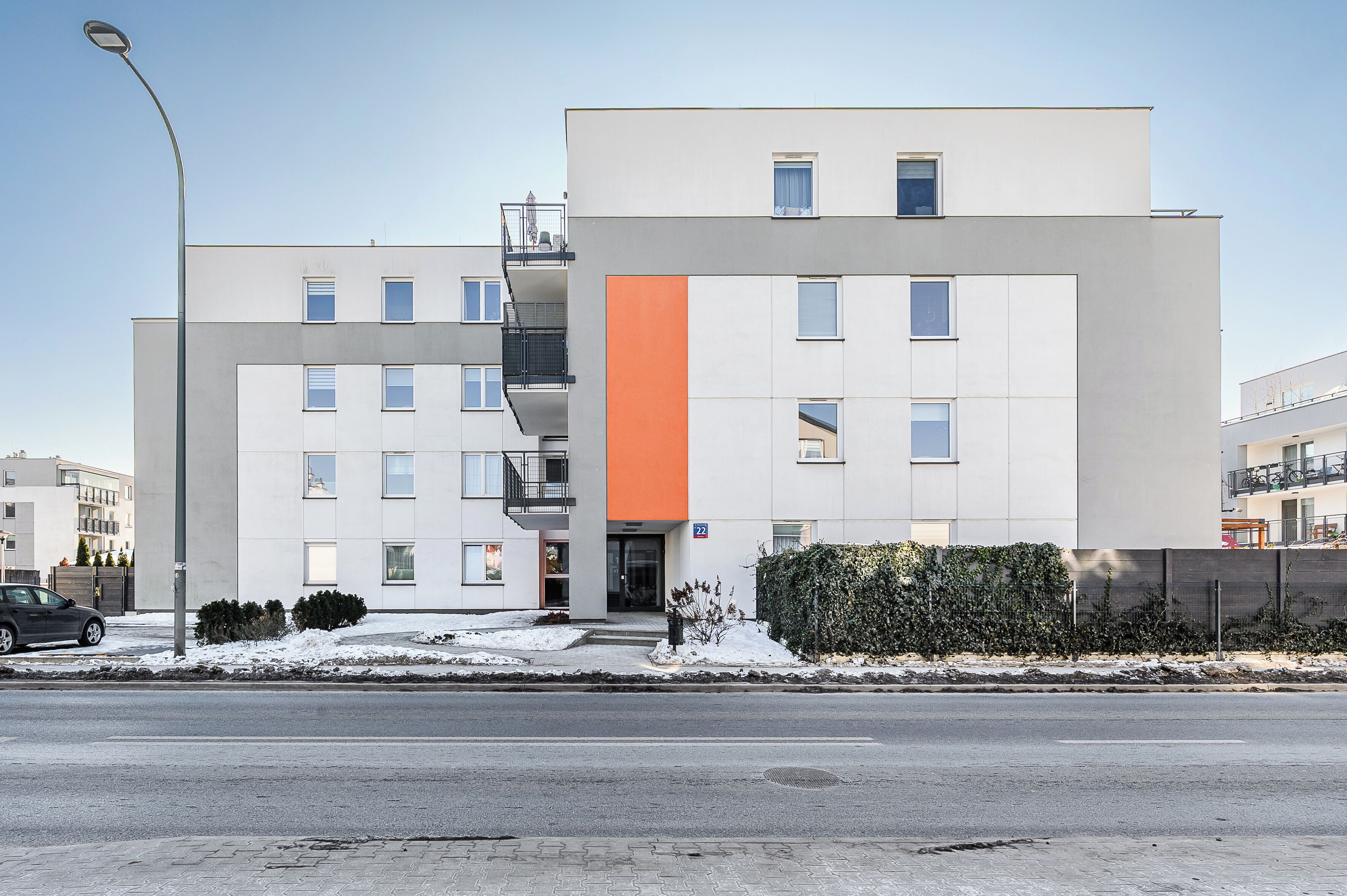 A modern building with a flat facade, multiple windows, and a visible entrance.