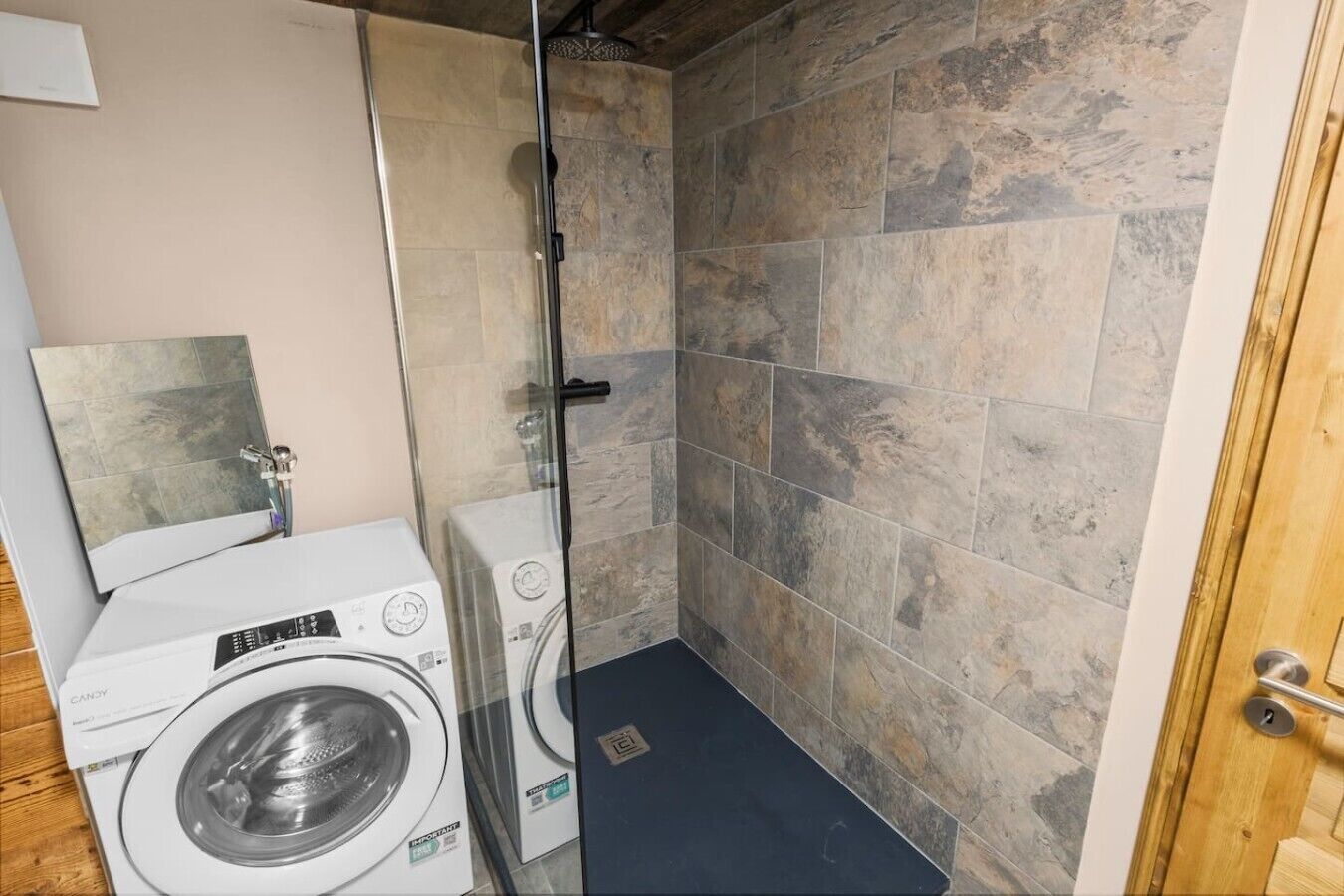 Ein kleines Badezimmer mit Dusche, Waschmaschine und Trockner.