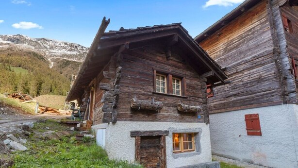 A rustic wooden house with a sloped roof, a small window with a door, and a stone foundation. - Cozy studio in the heart of an Alpine chalet (Anniviers)