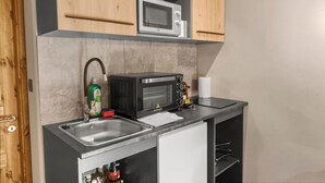 A kitchen with a microwave, sink, and cabinets. - Cozy studio in the heart of an Alpine chalet (Anniviers)