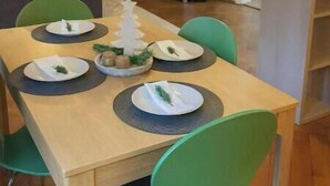 Ein Essbereich mit einem Holztisch, grünen Stühlen und einem Weihnachtsbaum als Mittelpunkt.